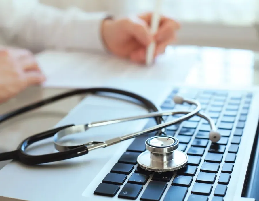 Health Information Management Professional Taking Notes by Laptop with Stethoscope